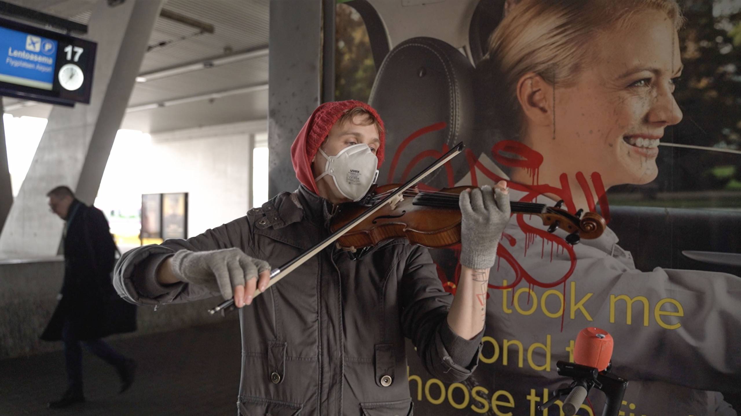 A man wearing a face mask plays the violin at the railway station.