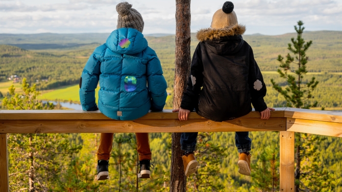 Vaatelaastarin tuotekuva. Kaksi lasta istuu katsomassa maisemaa, toppavaatteet on paikattu Vaatelaastareilla.