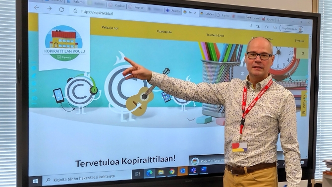 Kopioston erityisasiantuntija Mikko Löyttyniemi kouluttamassa. Hän seisoo ison näytön edessä ja osoittaa näyttöä. Näytöllä näkyy Kopiraittilan verkkosivut.