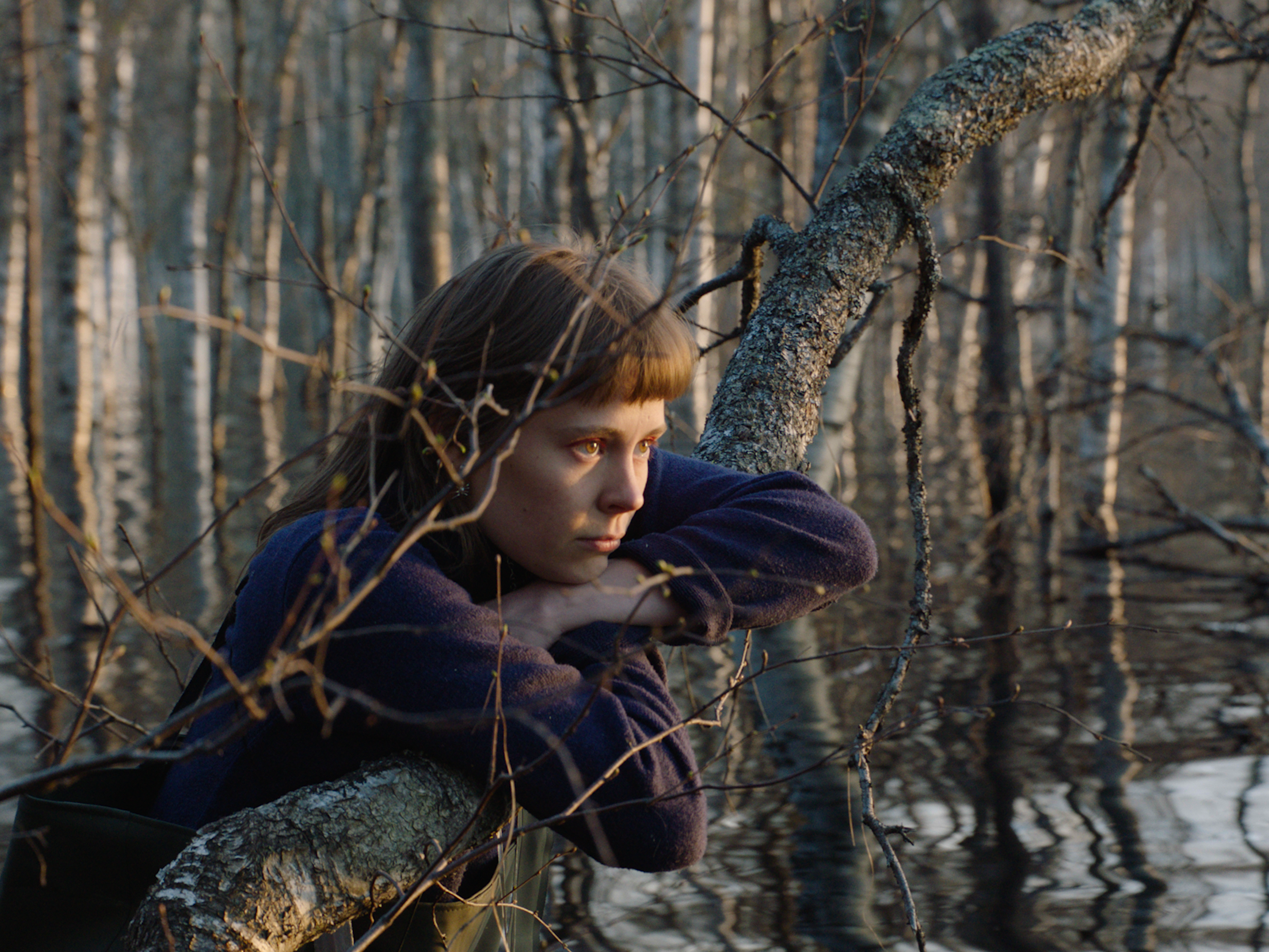 Still-kuva elokuvasta. Minka on metsässä, nojaa puunrunkoon.