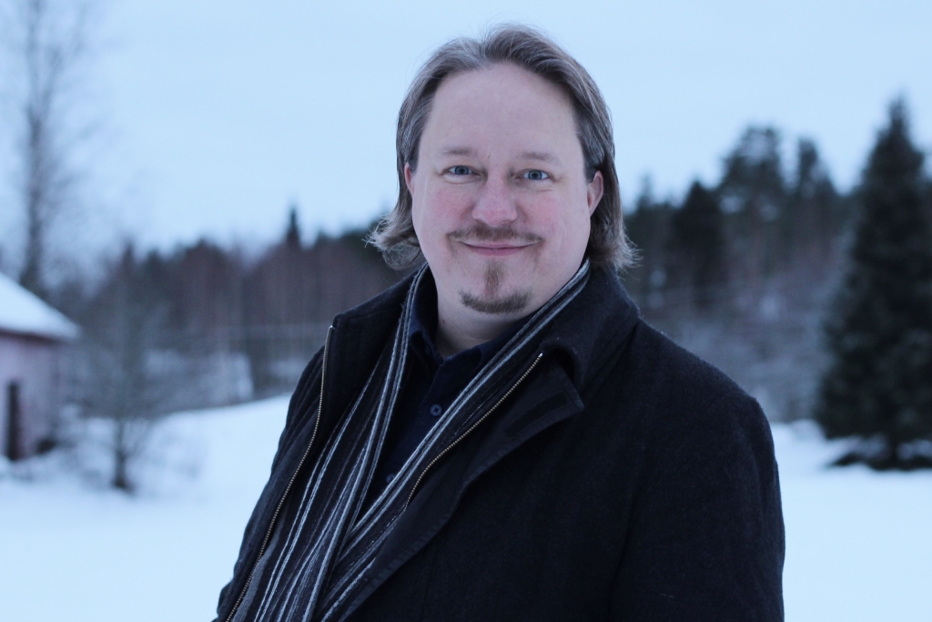 Mikko Peltonen katsoo kameraan ja hymyilee, taustalla talvinen maisema.